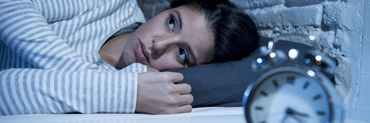 Frau im Bett Wecker schlaflos