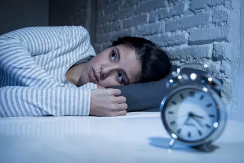 Frau im Bett Wecker schlaflos