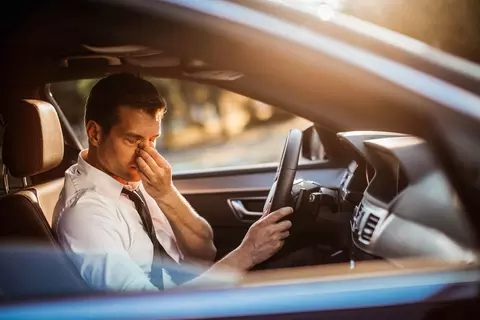 Mann gestresst und erschöpft im Auto