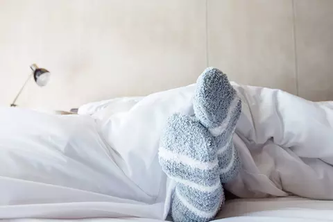 Person liegt mit Socken im Bett